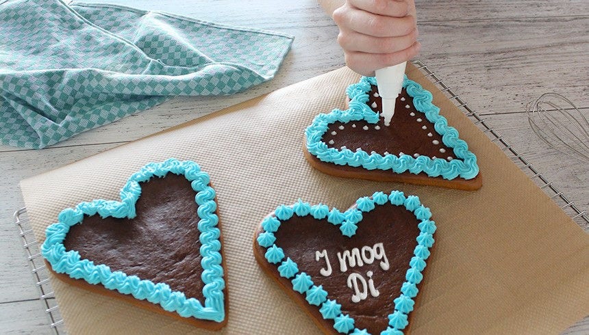 Dekorere pepperkakehjerter med sprøyteposer laget av bakepapir