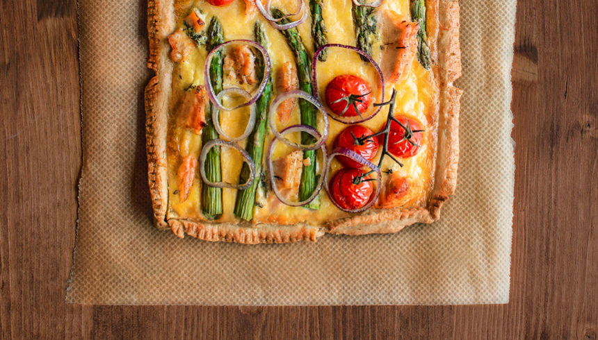 Sammenkomst og snacks med quiche på smørdeig med egg, asparges og løk